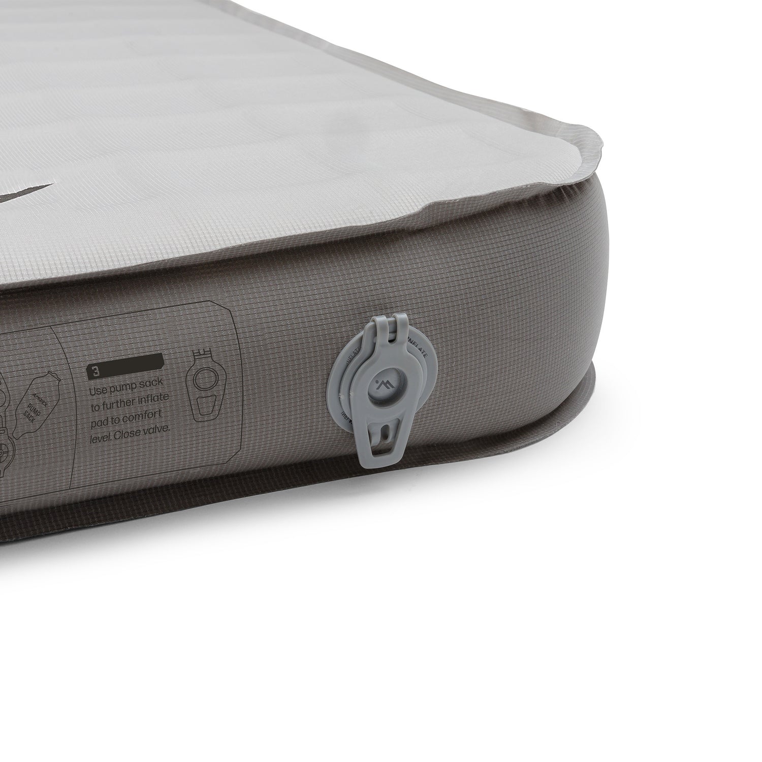 Close-up of the pad’s side corner with inflation valve, textured fabric, and printed instructions.