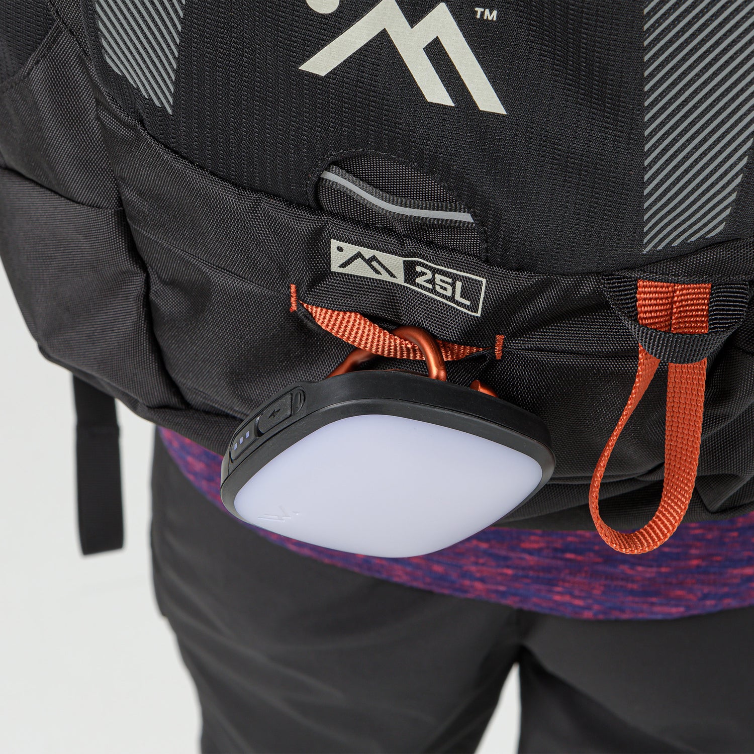 Lower front pocket of the pack with orange zipper holding a compact round light.