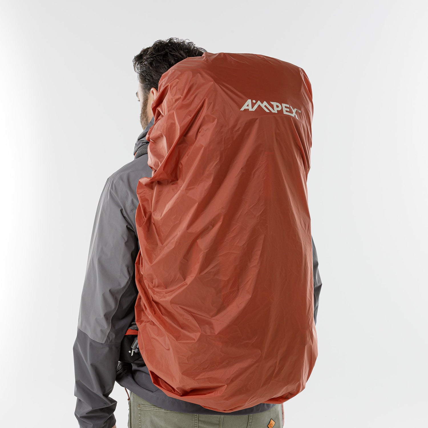 Backpack covered with orange Ampex rain cover for weather protection.