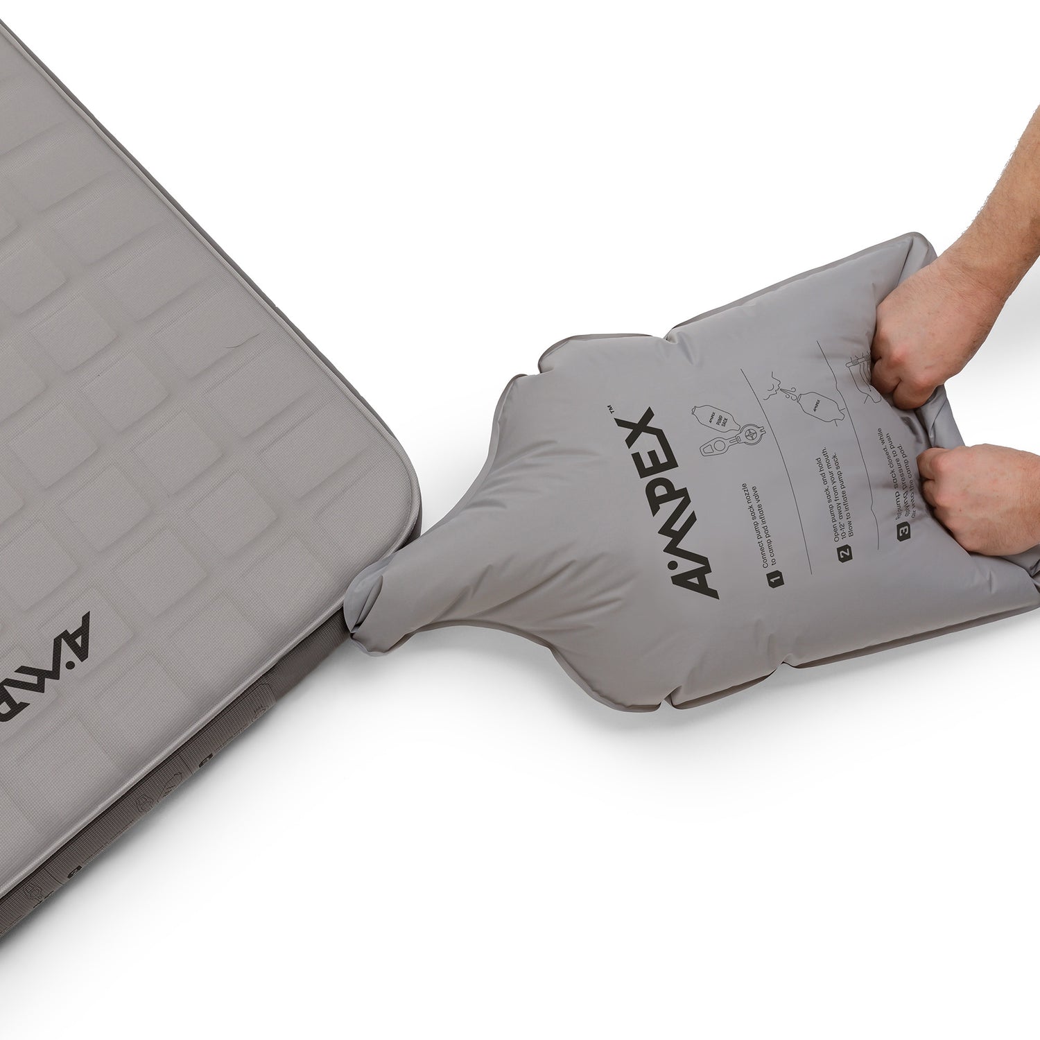 A person using the included pump sack to inflate their sleeping pad.