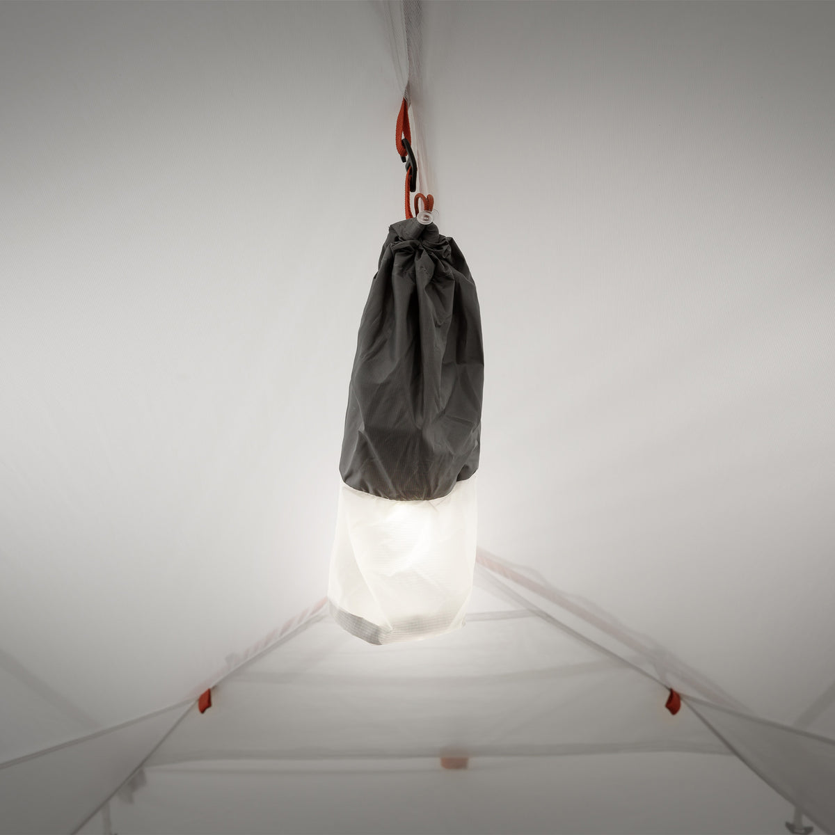 White and black gear sack hanging from the tent ceiling loop.