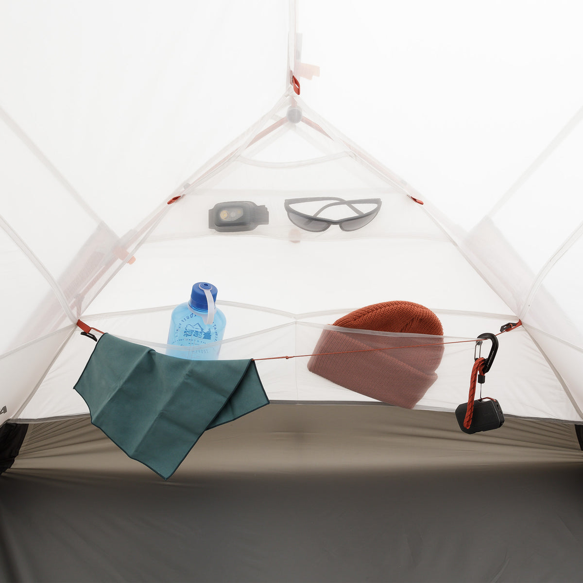 Mesh wall pockets inside tent holding a water bottle, hat, and sunglasses.