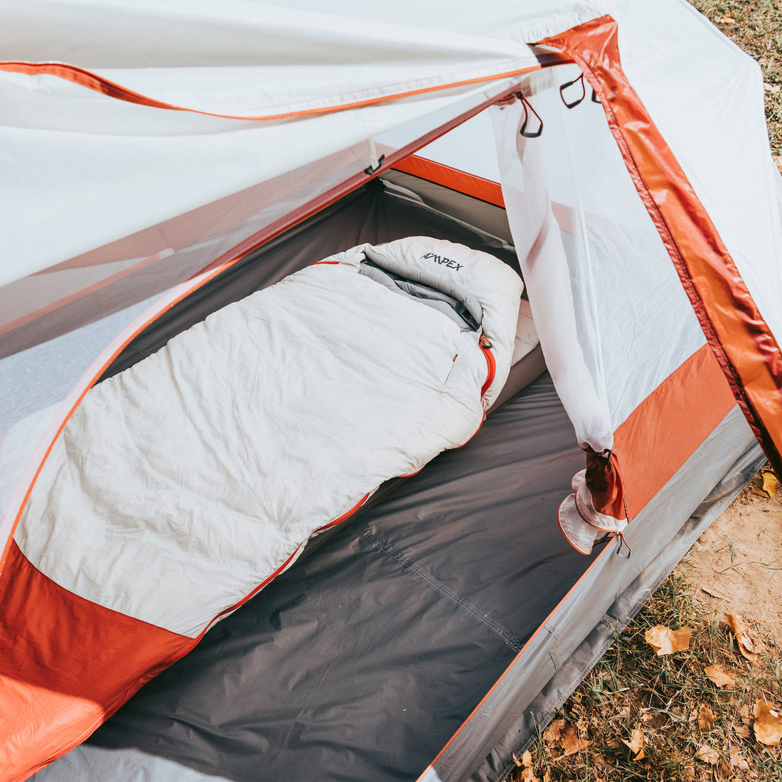 Sleeping bag laid out inside an orange and white camping tent.