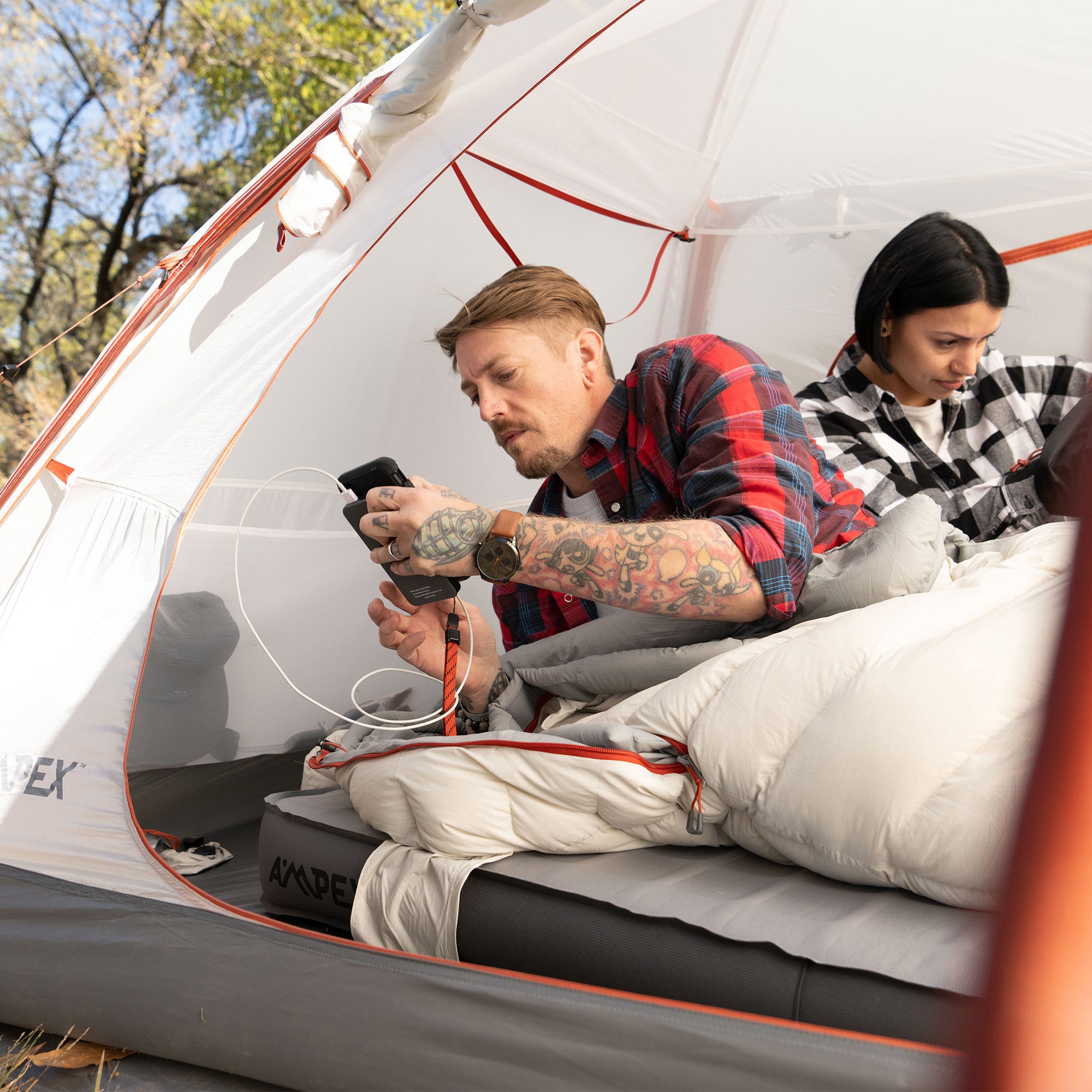 Person using the Power Bank inside a tent with another person.